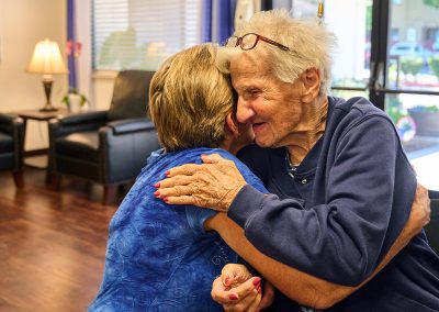 Two elderly ladies hugging at Arbor Place Residential